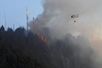 Un helicóptero combate hoy un incendio forestal en el cerro El Cable, en Bogotá (Colombia).