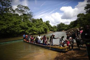 Fotografía de archivo de migrantes mientras descienden de una canoa antes de llegar a la Estación de Recepción Migratoria de Lajas Blancas, luego de atravesar la selva del Darién.