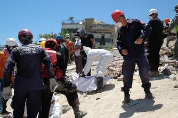 Bomberos y voluntarios rescatan un cuerpo sin vida durante los trabajos de remoción de escombros de los edificios Mision Vivienda OPPE, este martes en La Guaira, Venezuela.