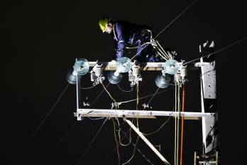 Fotografía de archivo de una persona trabajando en un poste de energía eléctrica.