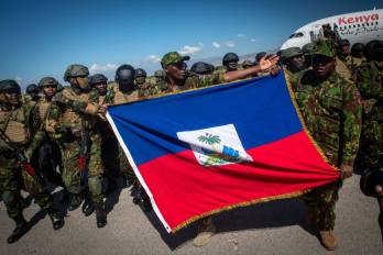 Policías kenianos sostienen una bandera de Haití a su llegada al aeropuerto internacional Toussaint Louverture este sábado, en Puerto Príncipe (Haití).