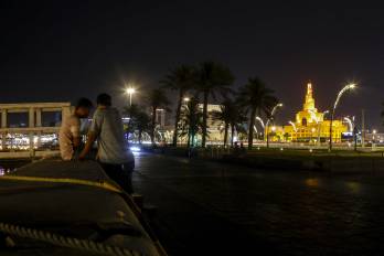 Hombres conversan en una calle de Doha, cerca de la Mezquita Fanar con su minarete en espiral, en Catar, el 23 de junio de 2025.