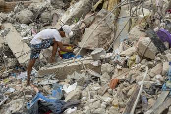 Una persona busca entre los escombros de edificios destruidos por terremotos en Caraballeda (Venezuela).