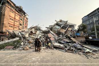 Personas permanecen junto a los escombros de un edificio derrumbado en Mandalay después del terremoto.
