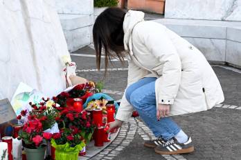 Una mujer coloca este jueves una vela en la estatua de Juan Pablo II ante el hospital Agostino Gemelli de Roma, donde el papa Francisco permanece hospitalizado.