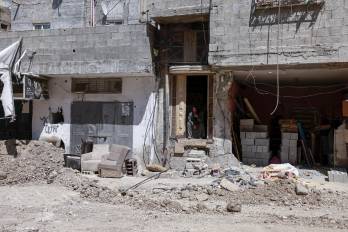 Una mujer observa desde la entrada de su casa, junto a una carretera dañada, tras una redada del ejército israelí en Tulkarem, en la Cisjordania ocupada, el 3 de agosto de 2024.