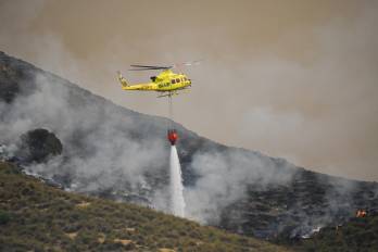 Un helicóptero del servicio de extinción de incendios arroja este viernes agua sobre uno de los focos del incendio forestal declarado en Los Gallardos, Almería, que se ha convertido en una tragedia sin precedentes en la zona.
