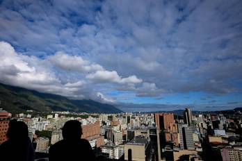La gente en una cafetería conversa mientras disfruta de la vista de la ciudad de Caracas.
