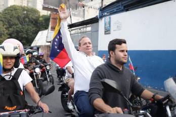 El opositor Juan Pablo Guanipa (c), cercano a la líder María Corina Machado, sostiene una bandera de Venezuela durante una caravana tras ser excarcelado este domingo, en Caracas (Venezuela).