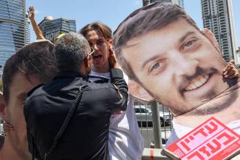 Un miembro de las fuerzas de seguridad israelíes se enfrenta con un manifestante que sostiene una silueta de un rehén, durante una protesta antigubernamental en Tel Aviv.