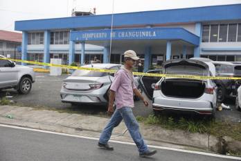 Una persona camina frente a algunos vehículos vandalizados en la entrada del aeropuerto de Changuinola este viernes, en Changuinola (Panamá).