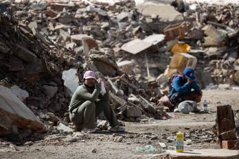 Personas esperan este lunes junto a los escombros de un edificio afectado por los terremotos en La Guaira (Venezuela).