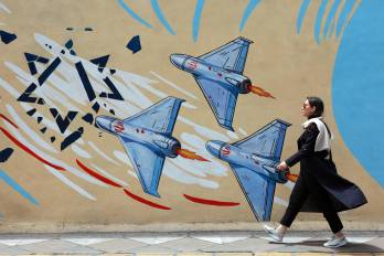 Una iraní camina junto a un mural anti-EE. UU. e Israel en una calle de Teherán, Irán.