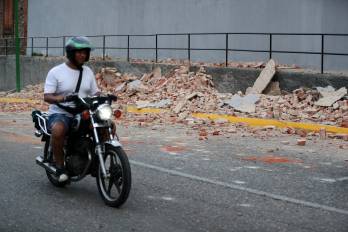 Un motociclista transita cerca de escombros este miércoles, en Caracas.