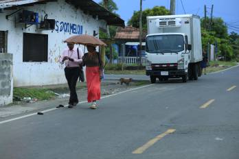 Personas caminan cerca de los vehículos debido al deterioro de aceras en Panamá.