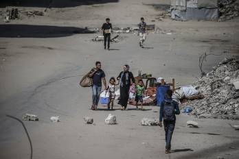 Los palestinos desplazados internamente se mueven con sus pertenencias antes de un ataque aéreo israelí en la ciudad de Gaza.