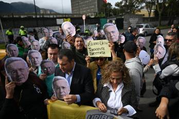 Partidarios del expresidente colombiano Álvaro Uribe portan máscaras con su rostro mientras esperan el veredicto de su juicio frente al Complejo Judicial de Paloquemao en Bogotá el 28 de julio de 2025.