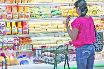 Una mujer observa los productos exhibidos es una estantería de un supermercado de la localidad.