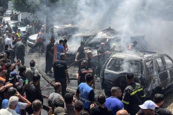 Personal de emergencia y residentes se congregan en el lugar donde un ataque aéreo israelí impactó un automóvil en Sidón, ayer miércoles.