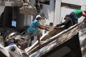 Personas observan los escombros de edificaciones colapsadas por el terremoto de magnitud 7,4 que sacudió esta mañana el país, este lunes en Cali (Colombia).