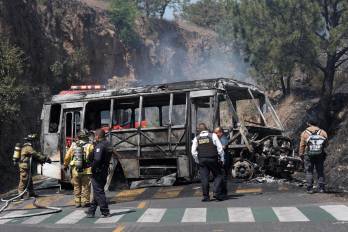 Bomberos e integrantes de la policía de Morelia trabajan en la zona donde fue incendiado un autobús por presuntos integrantes del crimen organizado este domingo, tras el abatimiento de Nemesio Oseguera Cervantes, alias El Mencho.