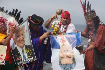 Un grupo de chamanes y curanderos sostienen carteles con las imágenes de los presidentes de Estados Unidos, Donald Trump, y de Venezuela, Nicolás Maduro, durante un ritual de fin de año frente al océano Pacífico este lunes, en Lima (Perú).
