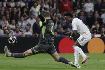 El delantero del Real Madrid Vinícius Junior (der.) chuta ante el portero Manuel Neuer, del Bayern Múnich.