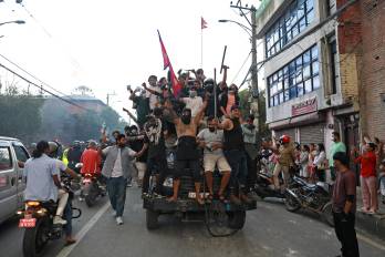 Manifestantes portan la bandera nacional de Nepal mientras viajan en un camión policial frente a la Casa Presidencial en Katmandú el 9 de septiembre de 2025, un día después de la represión policial contra las manifestaciones por la prohibición de las redes sociales y la corrupción gubernamental.