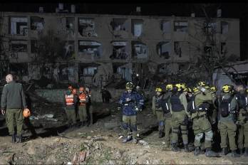 Esta captura de imagen tomada de un video de AFPTV muestra a equipos de emergencia inspeccionando el lugar de un ataque con misiles iraníes en Dimona el 21 de marzo de 2026.