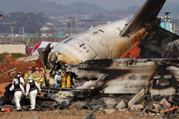 Los bomberos trabajan en los restos del avión Jeju Air siniestrado este domingo en el aeropuerto surcoreano de Muan.
