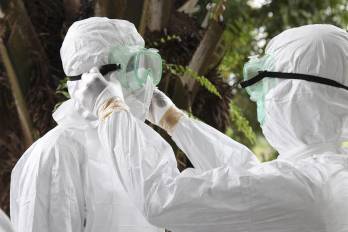 En la imagen de archivo, dos enfermeros liberianos mientras revisan sus equipos de protección individual antes de transportar el cuerpo de una víctima del ébola para su entierro.