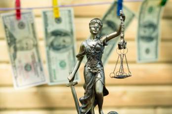 money laundering concept: image of Themis goddess or lady justice holding scale blindfold &amp; USD dollar bank notes hanging on the copy space background
