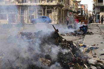Personas caminan cerca de un incendio en un vertedero de basura ubicado en una calle de La Habana, el 14 de julio de 2026.