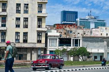 Un hombre camina por una calle mientras un coche clásico pasa a su lado, con el hotel Iberostar Selection (C) y el hotel Habana Libre Melia (D) al fondo, en La Habana, el 2 de junio de 2026.