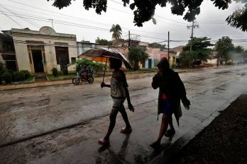 Personas se protegen de la lluvia este martes, en Santiago de Cuba (Cuba). EFE/ Ernesto Mastrascusa