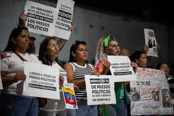 Personas sostienen carteles afuera de El Helicoide este lunes, en Caracas (Venezuela). EFE/ Ronald Peña R