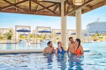 Fotografía cedida por Carnival Cruise Line que muestra personas hablando en la piscina de un hotel en Isla Tropicale en Roatán (Honduras).