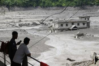 Varias personas observan cómo las aguas de la inundación arrasan Trishuli Bazar tras una crecida repentina, en el distrito de Nuwakot, Nepal.