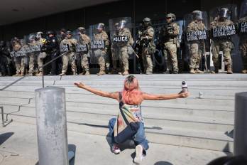 Una manifestante se arrodilla frente a miembros de la Guardia Nacional de California este lunes, frente al edificio federal Edward R. Roybal en Los Ángeles, California (Estados Unidos).