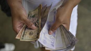 Una mujer cuenta billetes de bolívares y dólares estadounidenses en el barrio de Petare, en Caracas.