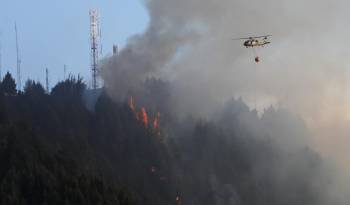 Un helicóptero combate hoy un incendio forestal en el cerro El Cable, en Bogotá (Colombia).