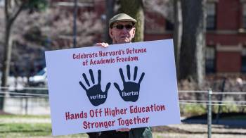 Un miembro del profesorado de Harvard sostiene un cartel al salir de Harvard Yard tras una manifestación contra los ataques del presidente Donald Trump a la Universidad de Harvard en Cambridge, Massachusetts, el 17 de abril de 2025.