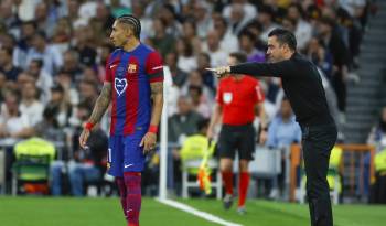 El entrenador del FC Barcelona, Xavi Hernández (d), y el delantero brasileño Raphinha (i) en el estadio Santiago Bernabéu de Madrid.