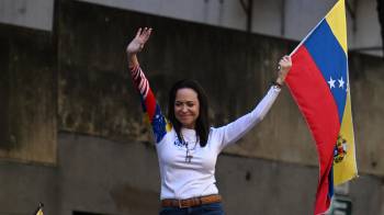 La líder opositora venezolana María Corina Machado ondea una bandera durante una protesta convocada por la oposición en vísperas de la investidura presidencial.