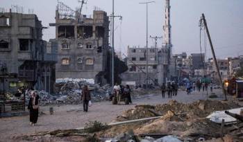 Desplazados internos caminan entre edificios derruidos tras recibir la orden del Ejército israelí de evacuar la localidad de Khan Younis, en la franja de Gaza.