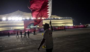 Un hombre sostiene una bandera de Catar antes de un evento deportivo.