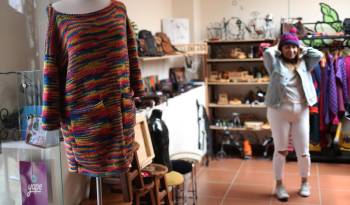 Una mujer probándose una prenda es vista al interior de una tienda que ofrece ropa confeccionada por internas de centros penitenciarios, el 6 de febrero de 2024, en La Paz (Bolivia).