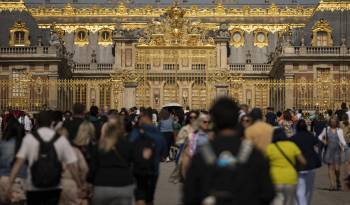 Los visitantes recorren las instalaciones frente a las puertas doradas del Palacio de Versalles, al suroeste de París, el 7 de junio de 2023.