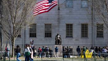 Manifestantes con pancartas se congregan alrededor de la estatua de John Harvard, en Harvard Yard, en protesta contra los ataques del presidente Donald Trump.
