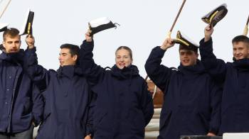 La princesa Leonor de Borbón (c) y demás tripulantes del buque escuela español Juan Sebastián de Elcano saludan al zarpar este domingo, en el muelle Prat, del puerto de Punta Arenas.